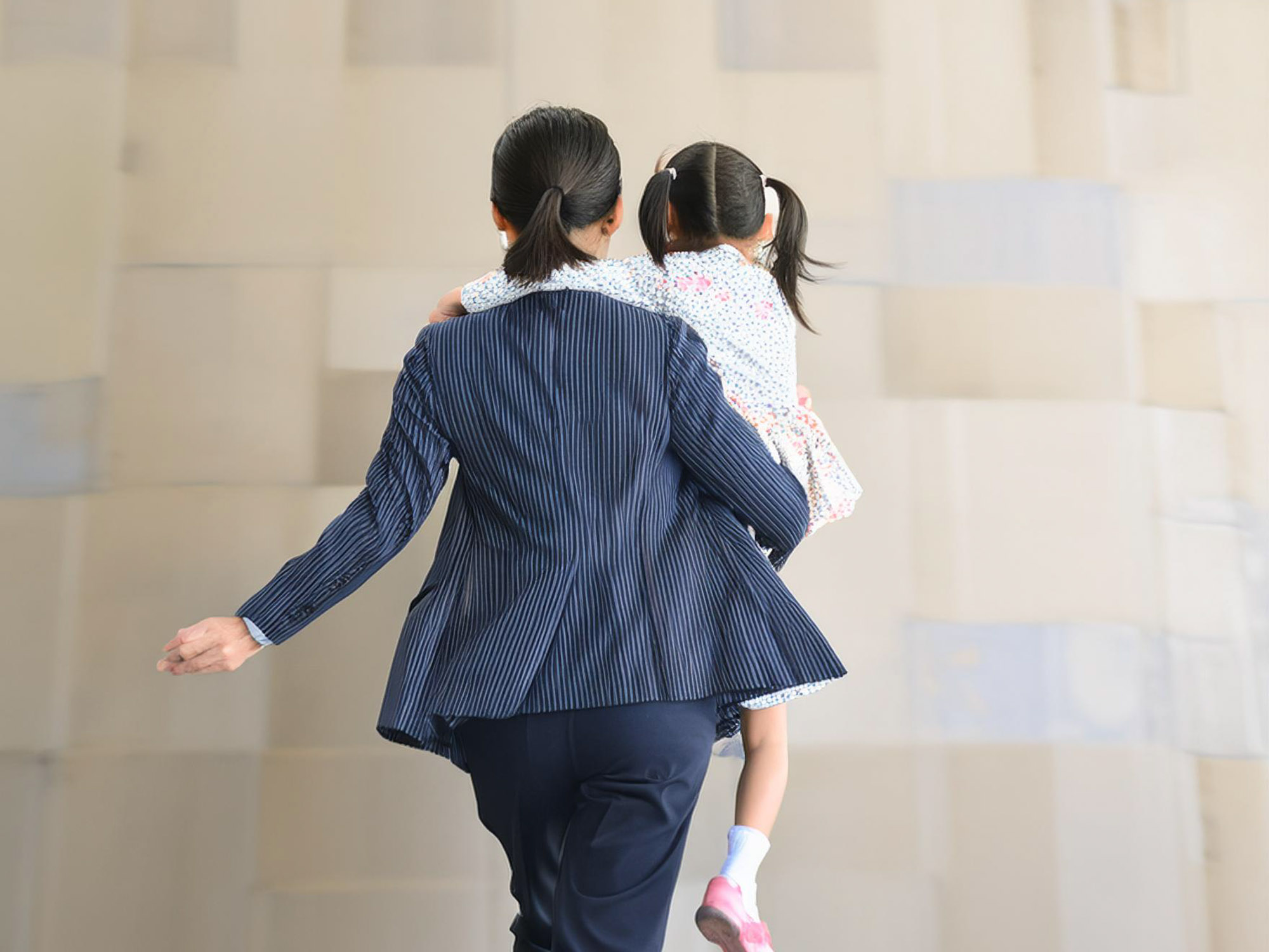 子どもを抱いて走るワーママ