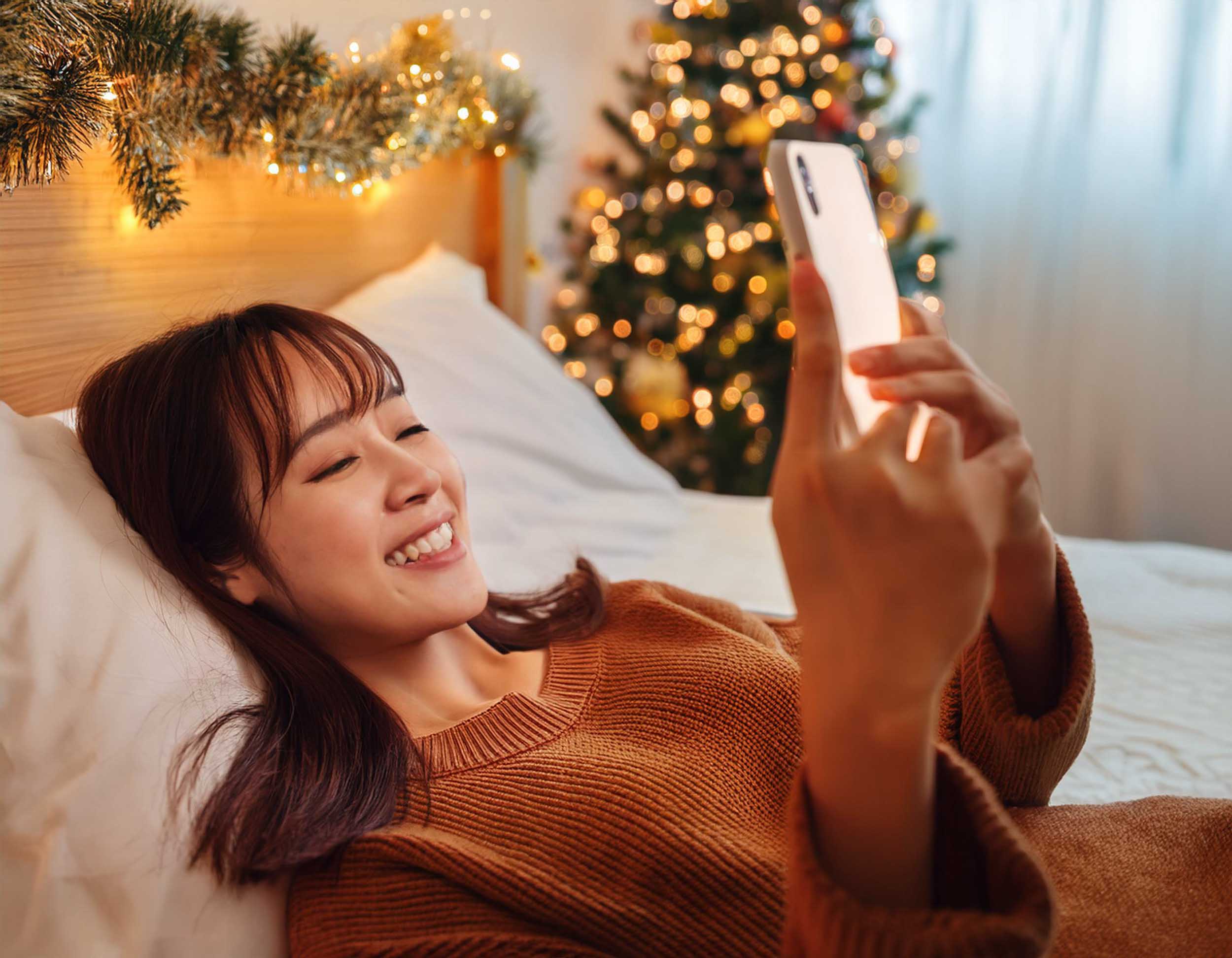 スマホを見ながら楽しそうに年末年始の旅行計画を立てている女性